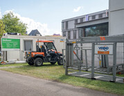 Backstage tijdens een evenement in een park, met gator en transportrekken voor bouw- en dranghekken.